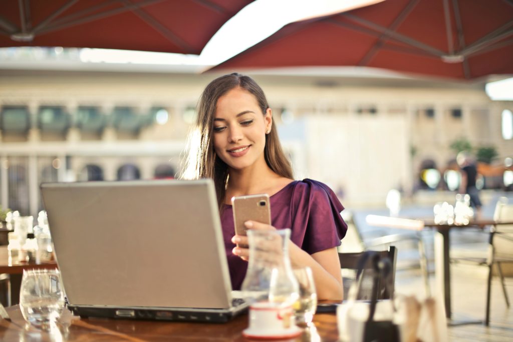 pexels-photo-826349-826349 Woman enjoying remote work at a café, using a laptop and smartphone.