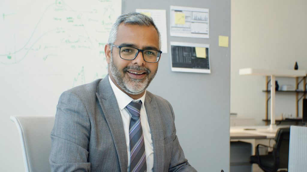 Confident senior businessman in suit and tie, smiling in modern office.